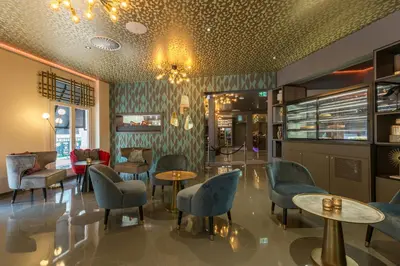 a restaurant with chairs and tables and a chandelier at Leonardo Hotel Amsterdam Museum Quarter in Amsterdam
