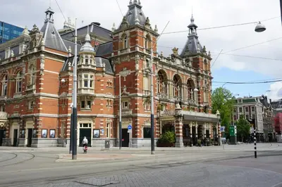 a large red brick building on a city street at Leonardo Hotel Amsterdam Museum Quarter in Amsterdam