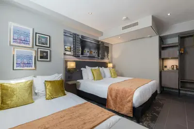 a hotel room with two beds and a kitchen at Leonardo Hotel Amsterdam Museum Quarter in Amsterdam