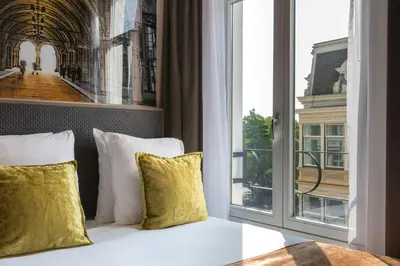 a bed with yellow pillows in a room with a window at Leonardo Hotel Amsterdam Museum Quarter in Amsterdam