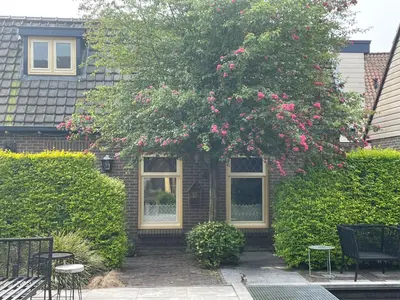a house with a large tree with pink flowers at Holiday in Spakenburg t Afferhuus in Spakenburg