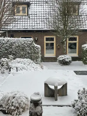 a snow covered yard with a bench in front of a house at Holiday in Spakenburg t Afferhuus in Spakenburg