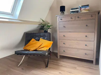 a chair with two yellow pillows on it next to a dresser at Holiday in Spakenburg t Afferhuus in Spakenburg