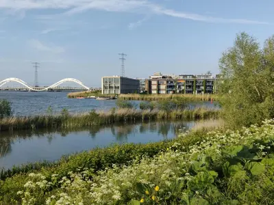 a river with buildings and a bridge in the background at House of Straw Amsterdam in Amsterdam