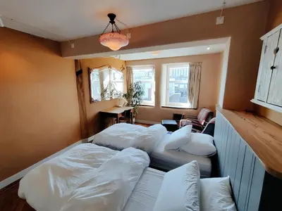 a room with three beds and a table and windows at House of Straw Amsterdam in Amsterdam