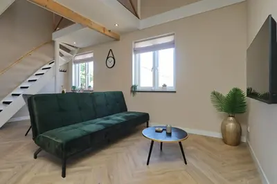 a living room with a green couch and a table at appartement-gratis parkeren -bij strand en in het centrum in Noordwijk