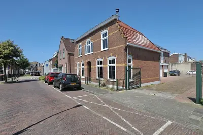 a brick building with cars parked on the side of a street at appartement-gratis parkeren -bij strand en in het centrum in Noordwijk