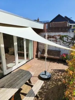 a white umbrella on a patio with a bench at Zilt aan Zee in Egmond aan Zee