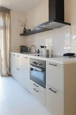 a kitchen with white cabinets and a stove top oven at Zilt aan Zee in Egmond aan Zee