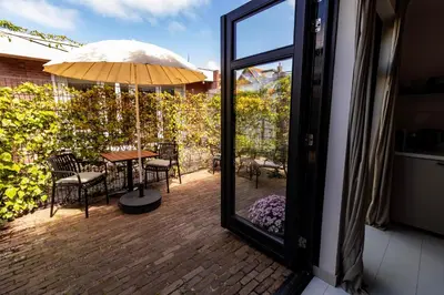 a patio with a table and chairs and an umbrella at Zilt aan Zee in Egmond aan Zee