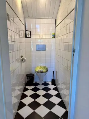 a bathroom with a toilet and a tiled floor at Ozzy's Beach House in Zandvoort