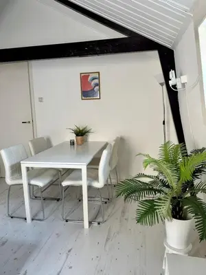 a white dining room with a white table and chairs at Ozzy's Beach House in Zandvoort