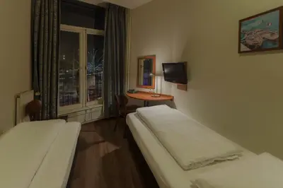 a room with two beds and a table with a window at A-Train Hotel in Amsterdam
