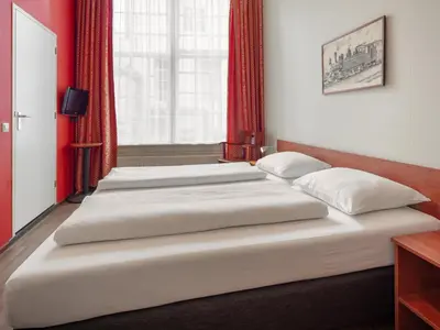 two beds in a room with red curtains at A-Train Hotel in Amsterdam