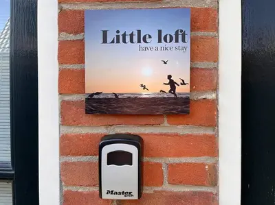 a sign on the side of a brick wall with a cell phone at Have a nice stay! - Little Loft, Summerhouse near the beach in Noordwijk aan Zee