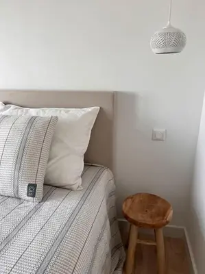 a bedroom with a bed with a wooden stool next to it at Have a nice stay! - Little Loft, Summerhouse near the beach in Noordwijk aan Zee