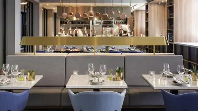 a restaurant with white tables and chairs and a counter at INK Hotel Amsterdam - MGallery Collection in Amsterdam