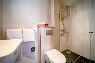 a bathroom with a shower and a toilet and a sink at OZO Hotels Cordial Amsterdam in Amsterdam
