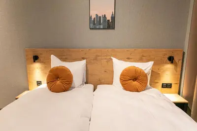 two beds with white sheets and orange pillows at Distrikt Hotels Amsterdam Zaandam in Zaandam