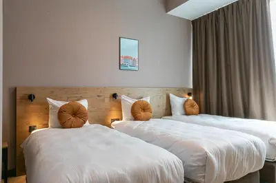 two beds in a hotel room with white sheets at Distrikt Hotels Amsterdam Zaandam in Zaandam