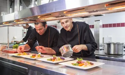 two chefs preparing plates of food in a kitchen at Fletcher Hotel-Restaurant De Klepperman in Hoevelaken