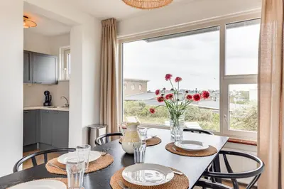 a dining room with a table and a large window at Vernieuwd Zeezicht Villa Strand Luxe in Bergen aan Zee