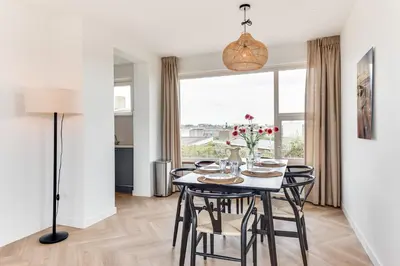 a dining room with a table and chairs and a window at Vernieuwd Zeezicht Villa Strand Luxe in Bergen aan Zee