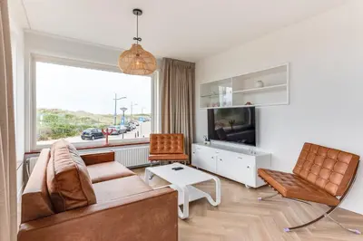 a living room with a couch and chairs and a tv at Vernieuwd Zeezicht Villa Strand Luxe in Bergen aan Zee