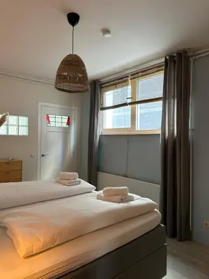 a bedroom with two beds and a large window at Salt Apartment in Zandvoort