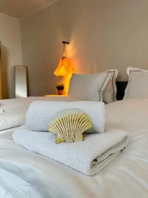 a pile of towels and a shell on a bed at Salt Apartment in Zandvoort