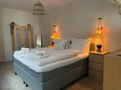 a bedroom with a large bed with two lights on it at Salt Apartment in Zandvoort