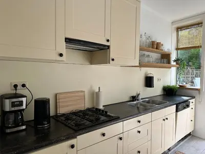 a kitchen with white cabinets and a sink and a stove at Salt Apartment in Zandvoort