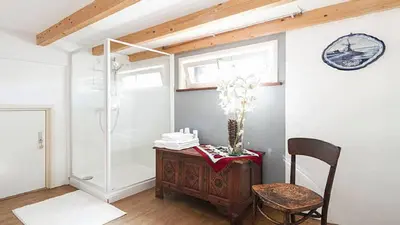 a bathroom with a table and a chair and a clock at Benedenverdieping in Woonboot met tuinterras in Utrecht