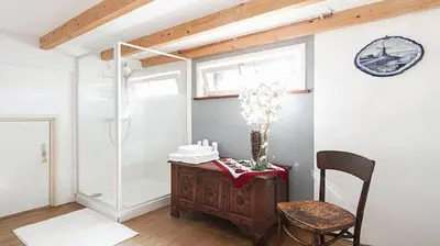 a bathroom with a shower and a table and a chair at Benedenverdieping in Woonboot met tuinterras in Utrecht