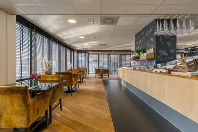 a restaurant with tables and chairs and a counter at Leonardo Hotel Lelystad City Center in Lelystad