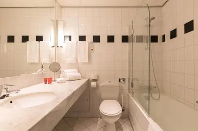 a bathroom with a toilet and a sink and a shower at Leonardo Hotel Lelystad City Center in Lelystad
