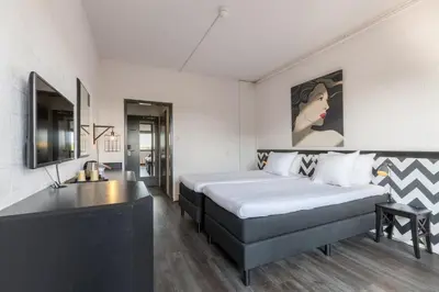 a bedroom with two beds and a painting on the wall at Leonardo Hotel Lelystad City Center in Lelystad