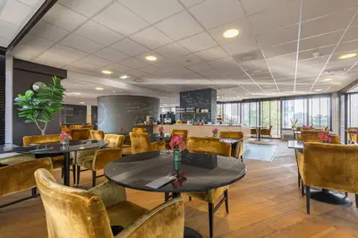 a restaurant with tables and chairs and a counter at Leonardo Hotel Lelystad City Center in Lelystad