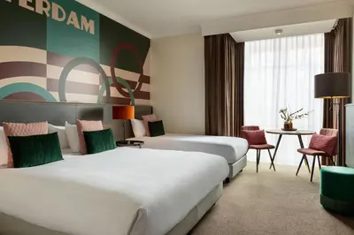 a hotel room with two beds and a table and chairs at Apollo Hotel Amsterdam, a Tribute Portfolio Hotel in Amsterdam