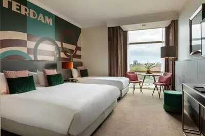 a hotel room with two beds and a table at Apollo Hotel Amsterdam, a Tribute Portfolio Hotel in Amsterdam