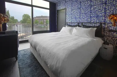 a bedroom with a large bed with a large window at Apollo Hotel Amsterdam, a Tribute Portfolio Hotel in Amsterdam