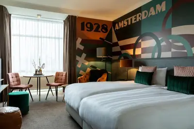 a hotel room with two beds and a table at Apollo Hotel Amsterdam, a Tribute Portfolio Hotel in Amsterdam