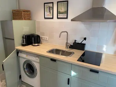 a kitchen with a sink and a washing machine at Beach Bliss in Noordwijk