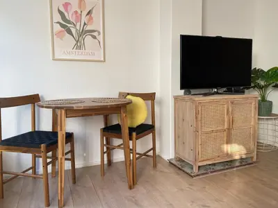 a living room with a table and a tv and chairs at Beach Bliss in Noordwijk