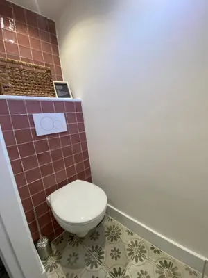 a bathroom with a toilet and a brown tiled wall at Beach Bliss in Noordwijk