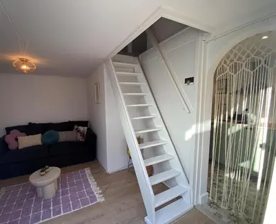 a staircase in a living room with a couch at Beach Bliss in Noordwijk