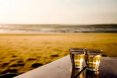 two glasses sitting on a table near the beach at Odyssee in Zandvoort