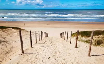a beach with a fence in the sand and the ocean at Odyssee in Zandvoort