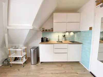 a kitchen with white cabinets and blue tiles at Odyssee in Zandvoort