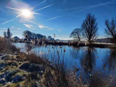 a body of water with the sun in the sky at Park De Driesprong in Nieuwveen